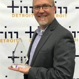 Smiling man holding clear triangular award