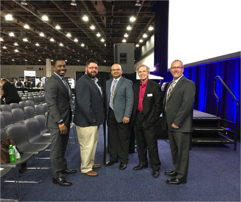 Five men in suits at conference venue